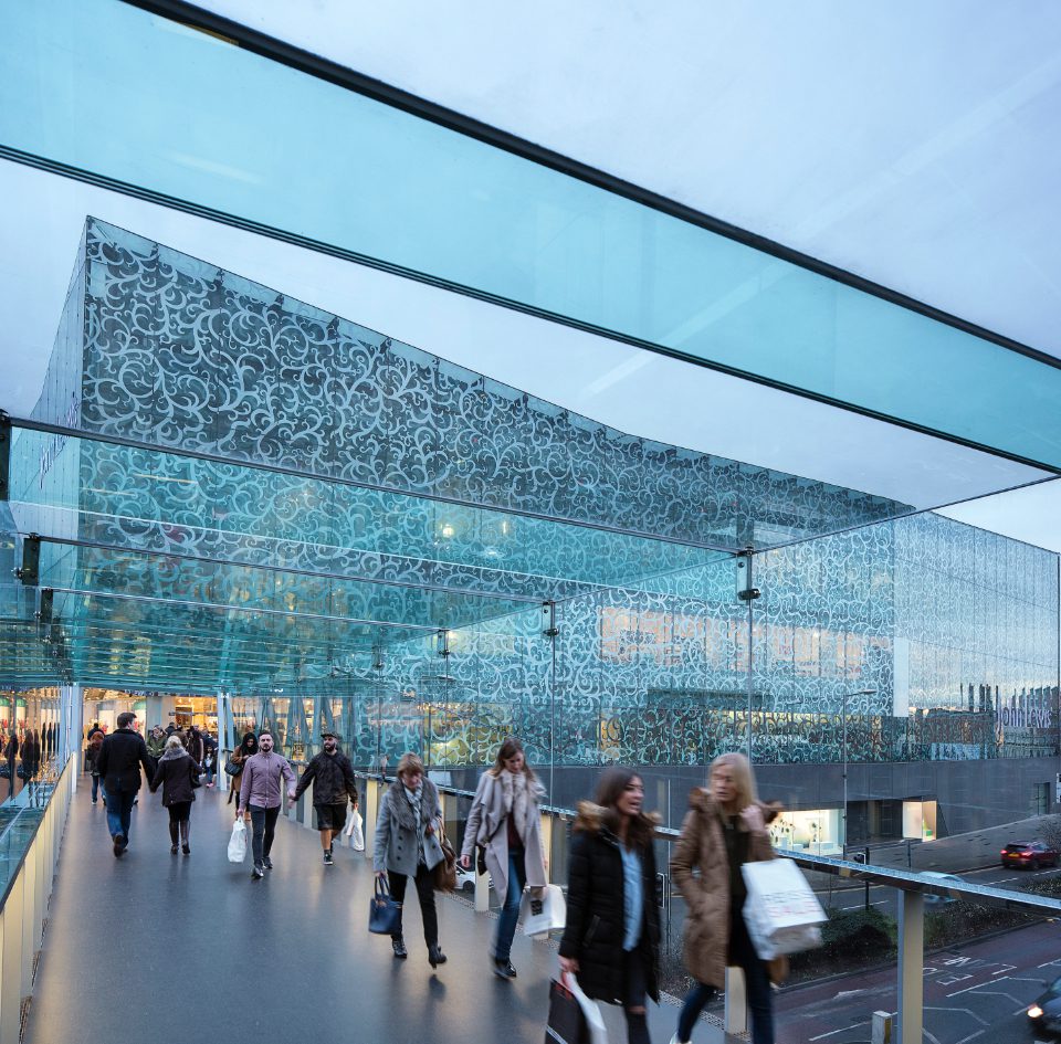 Lots of people carrying christmas shopping across Highcross bridge near John Lewis in Leicester