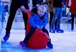 Young child using a skate aid on the real ice rink at Jubilee Square in Leicester