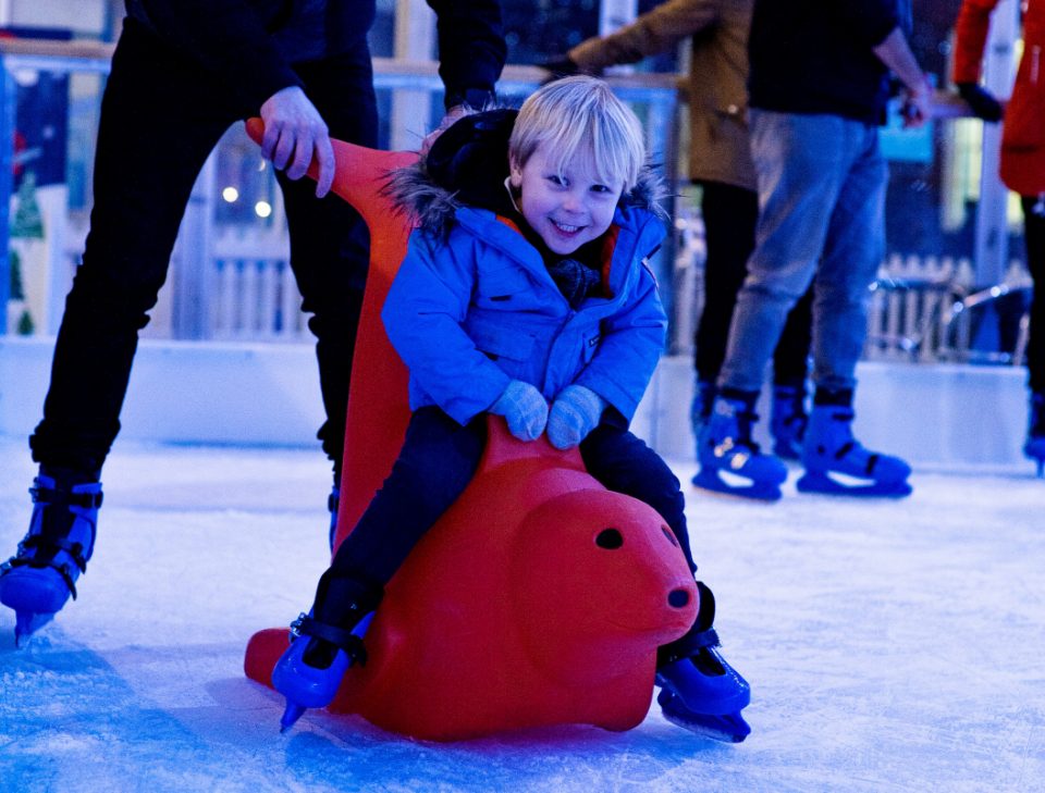 Young child using a skate aid on the real ice rink at Jubilee Square in Leicester