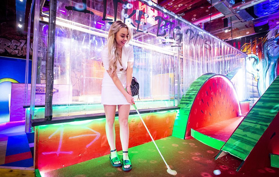 A woman takes a shot in a game of mini golf at Lane 7 in Leicester